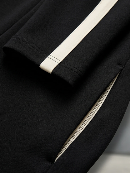 CIRILLA | Ensemble de sport noir avec demi-fermeture éclair, rayures contrastées et pantalon ample